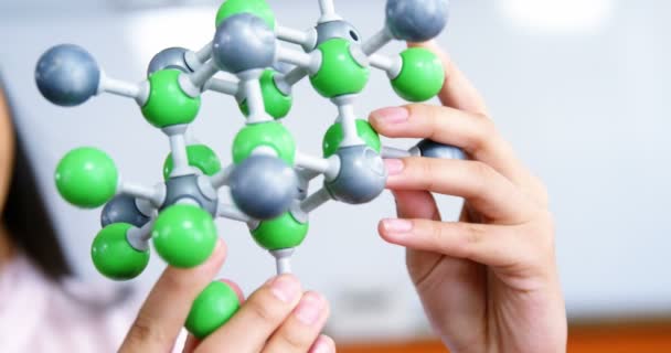 Schoolgirl experimenting molecule model in laboratory at school — Stock Video