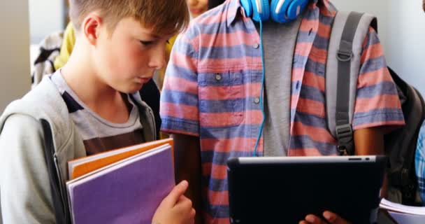 Estudiantes de pie con portátil y tableta digital en el pasillo — Vídeos de Stock
