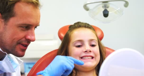 Dentist showing girls teeth on mirror — Stock Video