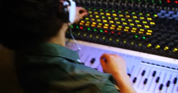 Mannelijke audio engineer hoofdtelefoon beluisteren tijdens het mixen van geluid — Stockvideo