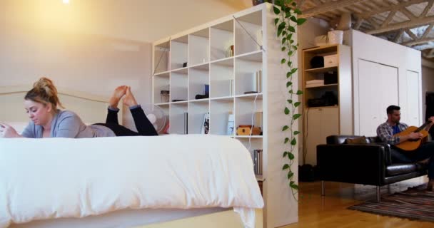 Man playing guitar while woman relaxing on bed — Stock Video