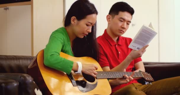 Пара, играющая на гитаре в гостиной — стоковое видео