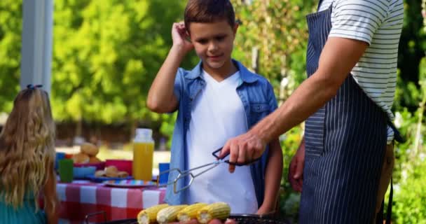 Padre e figlio grigliare salsicce e calli sul barbecue — Video Stock