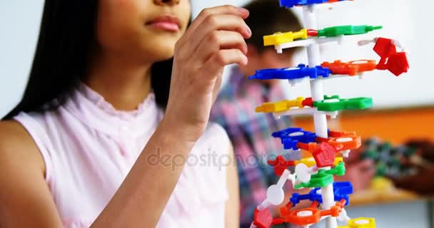 Schoolgirl experimenting molecule model in laboratory at school — Stock Video