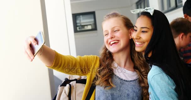 Estudantes sorrindo tirando selfie com telefone celular no corredor — Vídeo de Stock
