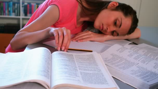 Κουρασμένος μαθήτρια ακουμπά στο γραφείο με βιβλιοθήκη — Αρχείο Βίντεο