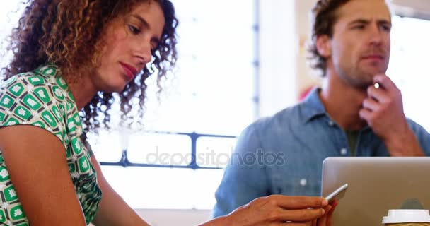 Женщина пользуется телефоном во время работы с коллегой — стоковое видео