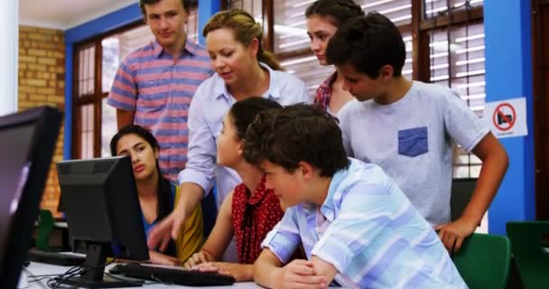 Учитель помогает студентам в компьютерном классе — стоковое видео