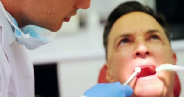 Dentistas examinando a un paciente masculino con herramientas — Vídeo de stock