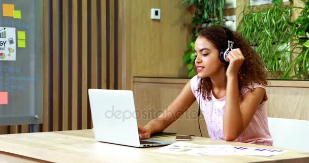 Esecutivo femminile ascoltare musica mentre si utilizza il computer portatile — Video Stock