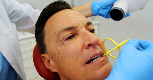 Dentista examinando a un paciente masculino con herramienta — Vídeos de Stock