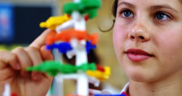 Schoolgirl experimenting molecule model in laboratory at school — Stock Video