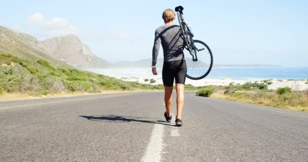 Triathlète homme portant le vélo dans la route de campagne — Video