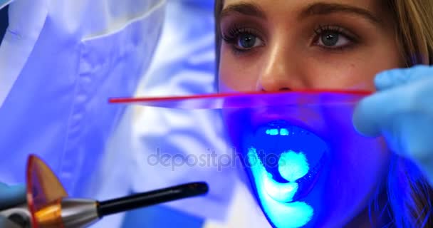 Стоматологи осматривают пациентку с помощью света для лечения зубов — стоковое видео