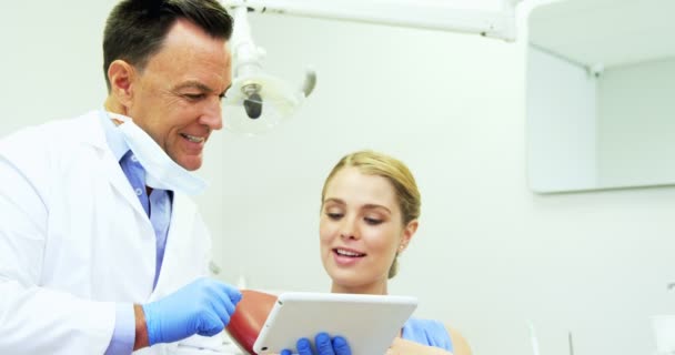 Dentista discutiendo sobre tableta digital con paciente femenino — Vídeos de Stock