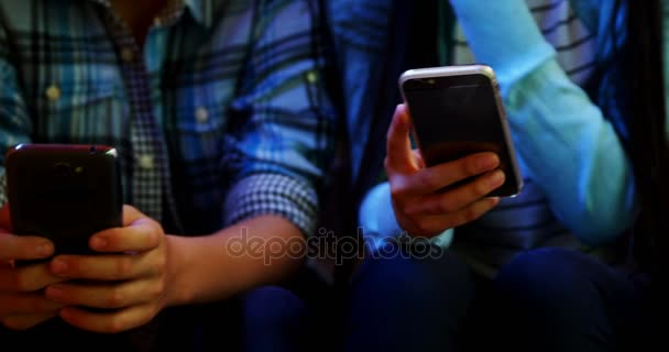 Sección media de amigos de la escuela usando el teléfono móvil en el pasillo — Vídeos de Stock