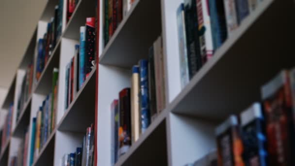 図書館の本棚から本を選択する男子生徒の手 — ストック動画
