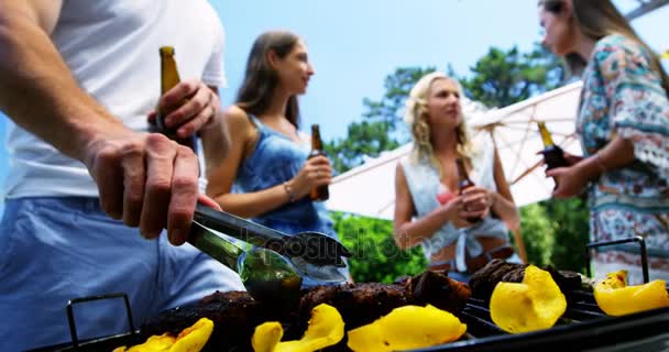 Gruppo di amici che bevono una bottiglia di birra mentre preparano il barbecue — Video Stock