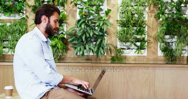Представитель мужского пола сидит за столом и пользуется ноутбуком — стоковое видео