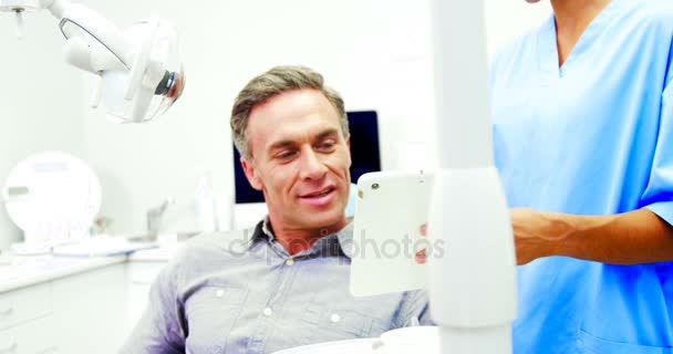 Dentista che mostra tablet digitale al paziente di sesso maschile — Video Stock