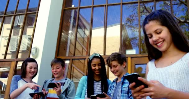 Groep van vrienden van de school gebruik mobiele telefoon buiten school — Stockvideo