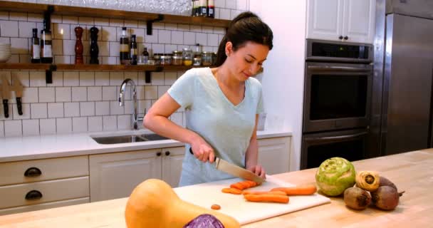 Γυναίκα σε φέτες καρότα στο πάγκο της κουζίνας — Αρχείο Βίντεο