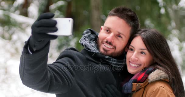 Pareja hablando y tomando una selfie con teléfono móvil en un día de invierno — Vídeo de stock