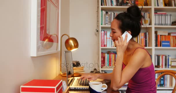 Mulher bonita no telefone celular usando laptop — Vídeo de Stock