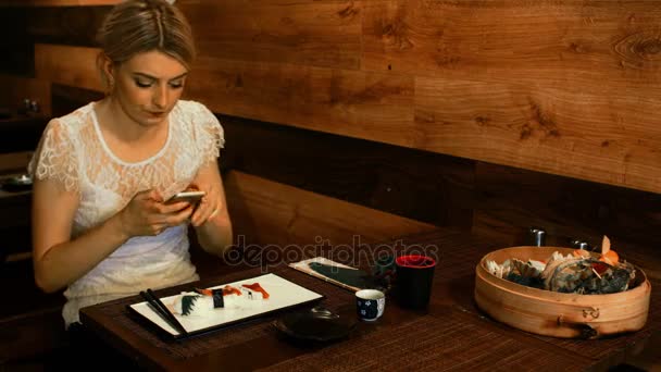 Kvinna med mobiltelefon samtidigt ha sushi — Stockvideo