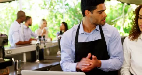 Мужчина и женщина официанты обсуждают за ноутбуком — стоковое видео
