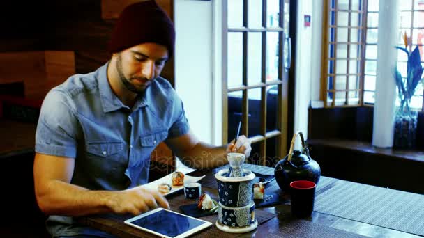 Ο άνθρωπος χρησιμοποιώντας ψηφιακό tablet ενώ έχοντας σούσι — Αρχείο Βίντεο
