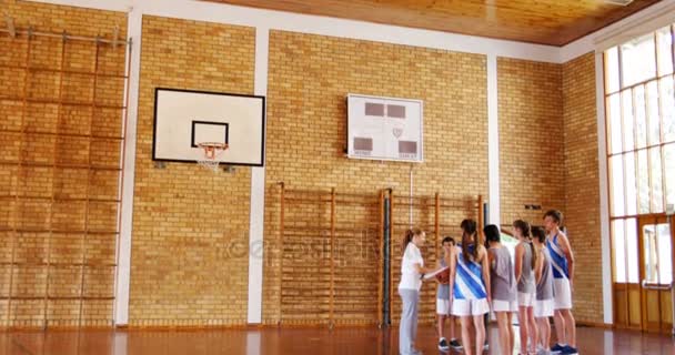 Female coach instructing school students in basketball court — Stock Video