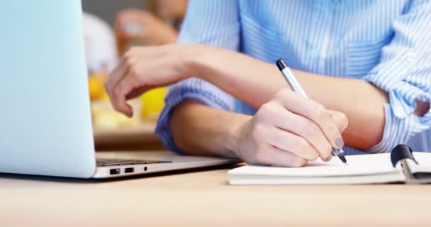 Ejecutiva femenina usando laptop y escribiendo en diario — Vídeos de Stock