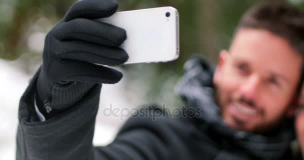 Пара разговаривающих селфи с мобильным телефоном в зимний день — стоковое видео