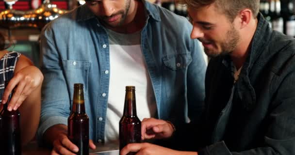 Улыбающаяся компания друзей с помощью цифровой тарелки во время распития пива — стоковое видео