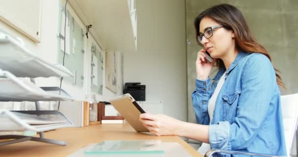 Ejecutivo femenino usando tableta digital mientras habla en el teléfono móvil — Vídeos de Stock