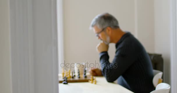 Чоловік має каву, граючи в шахи у вітальні — стокове відео
