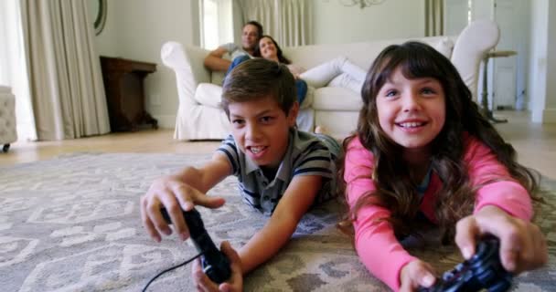 Siblings lying on rug and playing video game — Stock Video