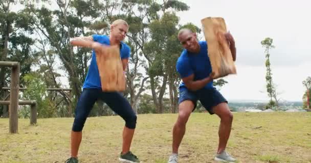 Man and woman lifting heavy wooden logs — Stock Video