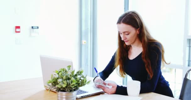 Führungskräfte schreiben Tagebuch, während sie auf Laptop schauen — Stockvideo