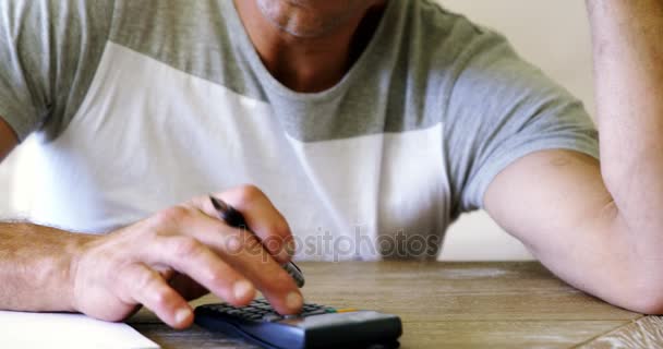 Homem tenso usando calculadora na sala de estar — Vídeo de Stock