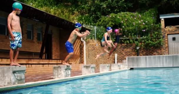 Schattige kleine kinderen springen in het zwembad — Stockvideo