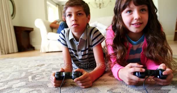 Τα αδέλφια ξαπλωμένος στο χαλί και παίζει βίντεο παιχνίδι — Αρχείο Βίντεο