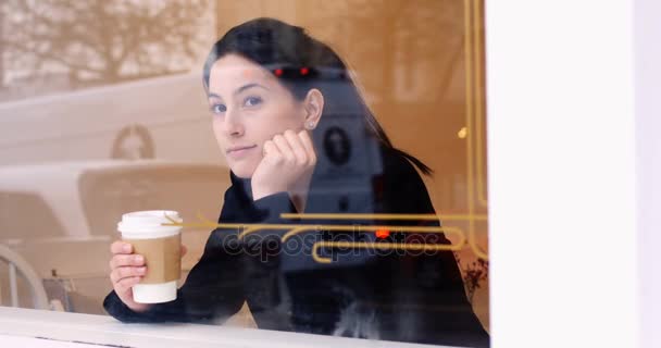 커피를 마시고 하는 동안 창문을 통해 보고 하는 여자 — 비디오