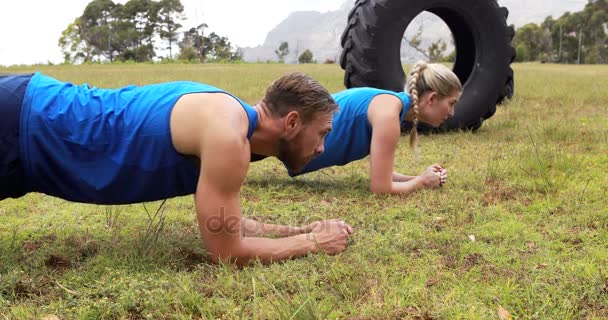 Homem e mulher se exercitando durante o curso de obstáculo — Vídeo de Stock