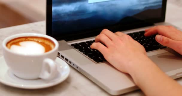 Mujer con taza de café usando portátil en la mesa — Vídeos de Stock