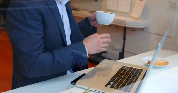Бізнесмен використовує ноутбук, маючи чашку кави — стокове відео