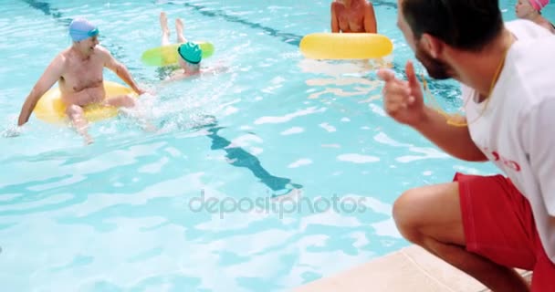 Treinador de natação auxiliando idosos na piscina — Vídeo de Stock