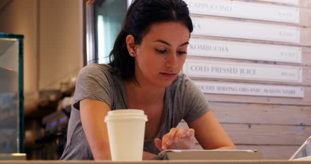 Kobieta z filiżanki kawy za pomocą cyfrowego tabletu na stole — Wideo stockowe