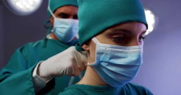 Surgeon helping a nurse in tying surgical mask — Stock Video